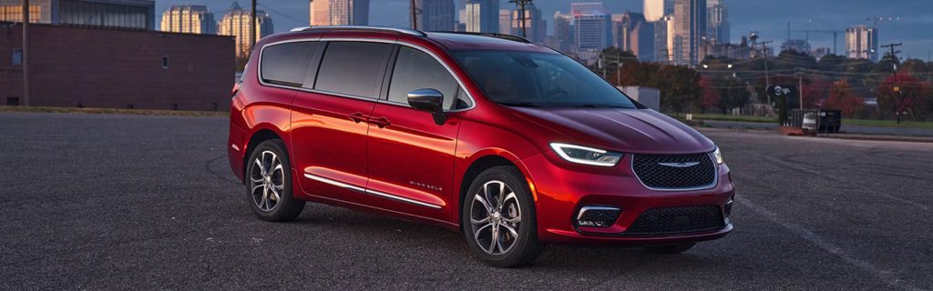 A red Chrysler minivan parked in an urban setting.