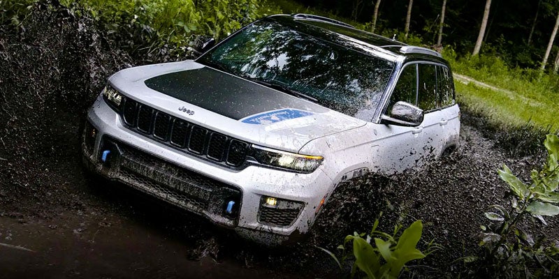 Jeep Grand Cherokee 4xe SUV splashing through muddy off-road trail