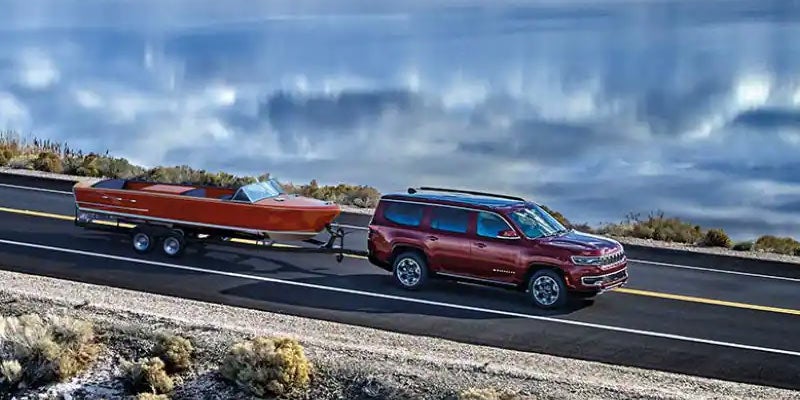 Jeep Grand Wagoneer SUV towing classic wooden boat.