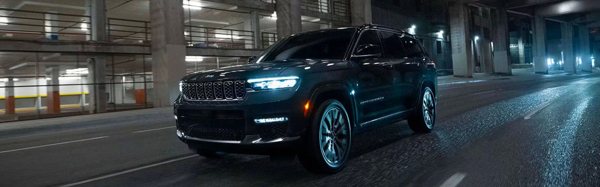Jeep Grand Cherokee SUV driving at night, headlights on.