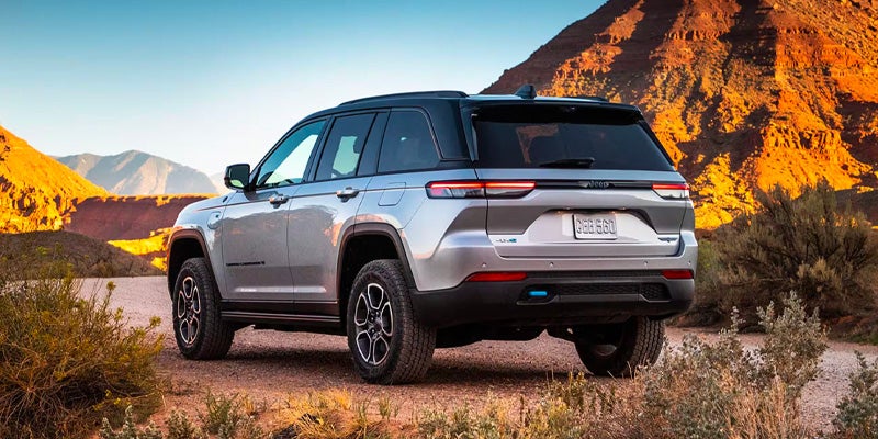 Jeep Grand Cherokee parked in desert with mountains backdrop