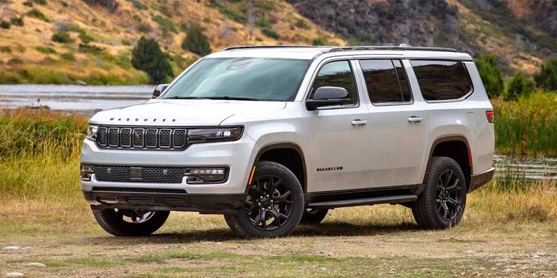 A Jeep Wagoneer parked in a grassy field