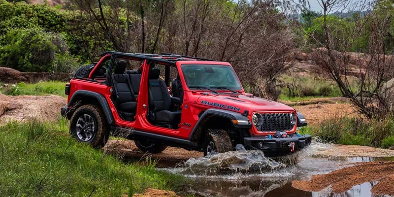 Jeep Wrangler driving through shallow water trail
