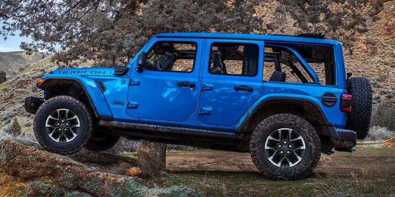 Jeep Wrangler 4xe climbing rocky terrain in natural landscape